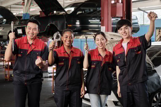 Multiracial professional mechanic workers team after work celebrating automotive repair jobs success, hand raises with fixing tools with cheerful smiles and look at camera at a service car garage. photo