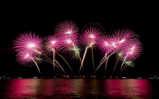 Amazing beautiful colorful fireworks display on celebration night, showing on the sea beach with multi color of reflection on water photo