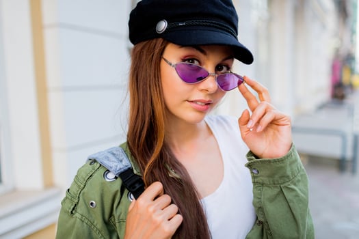 Happy brunette weoman posing outdoor . Stylish hat, sunglasses and green jacket. photo