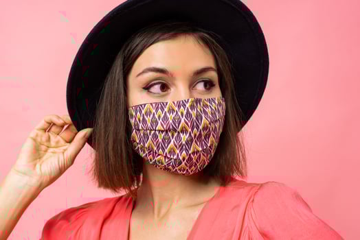 Close up portrait of  pretty woman dressed protective stylish face mask. Wearing black hat and sunglasses. Posing over pink background in studio. photo