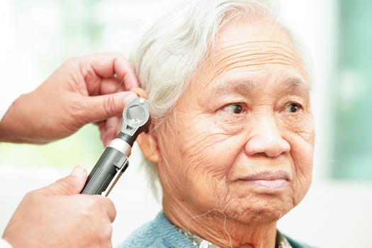 Otolaryngologist or ENT physician doctor examining senior patient ear with otoscope, hearing loss problem. photo