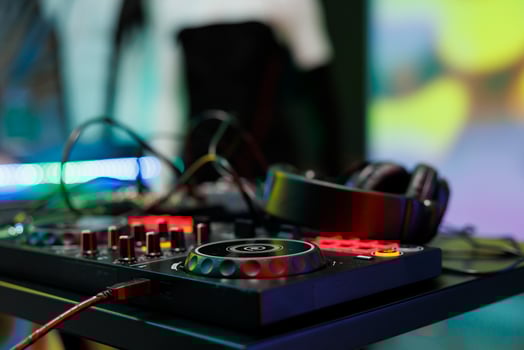 Dj controller with jog wheels, knobs and buttons for electronic music mixing at nightclub stage. Musician console panel and headphones for live performance in club close up photo