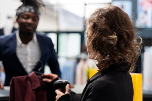 Shopaholic customer paying for fashionable clothes, making transaction on pos terminal in shopping center. Showroom manager scanning purchase using store scanner, commercial activity concept photo