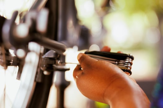 Image showcasing female hand using specialized equipment to adjust the valve on bike wheel. Detailed shot of african american person mending bicycle carefully using multipurpose tool. photo