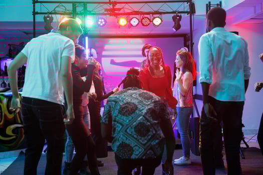 People dancing in nightclub full of young diverse clubbers having fun and enjoying live music. Happy friends moving to rhythm on dancefloor while attending disco party in club photo