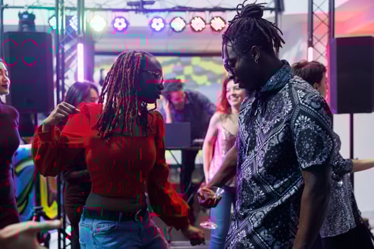 Young african american couple dancing and making moves to live music beats in crowded nightclub. Boyfriend and girlfriend dancers partying together on dancefloor in dark club photo