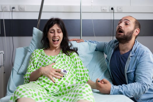 Future mother having painful contractions, getting into labor while nervous father yelling for doctor and medical assistance. Caucasian couple preparing for childbirth in hospital ward photo