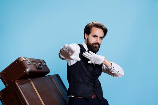 Groovy male bellhop dancing on camera, feeling happy and confident with silly dance moves in formal attire. Young professional doorman acting funky and fooling around in studio. photo