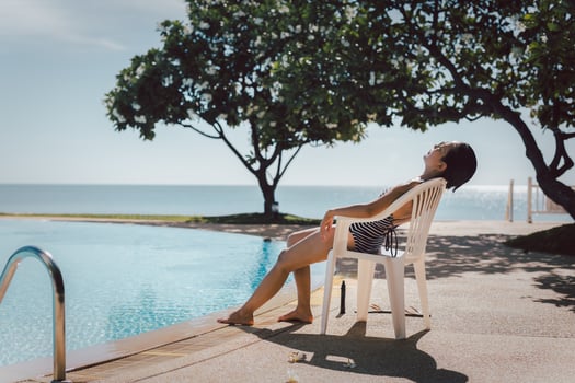 Woman having sunbathing by swimming pool outdoors at summer time. photo
