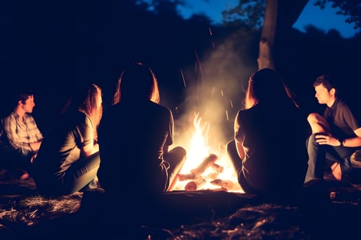 Friendship group sit round a bright campfire at night photo
