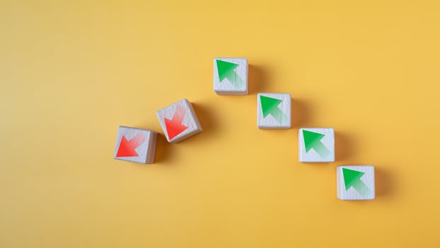 Green arrow and red arrow on wooden block represents economy trending downwards on yellow background. Economy recession crisis, inflation, stagflation, business and financial loss concept. photo