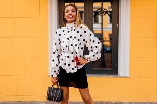 Outdoor image of lovable happy woman in stylish spring clothes with luxury  bag posing on the street over yellow background. photo