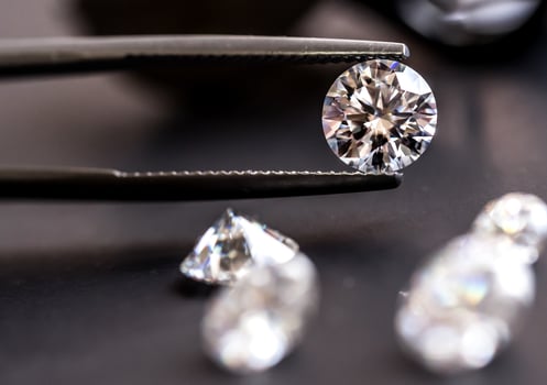 Diamond in tweezers on black background photo