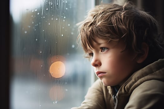 A sad little boy looking out the window on a rainy day. AI Generated photo