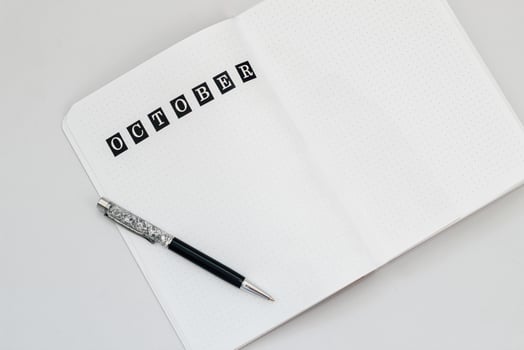 Filling in the diary, writing October in the notebook in a dot photo