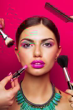Fashion portrait beautiful young female getting her make-up done against color background. photo