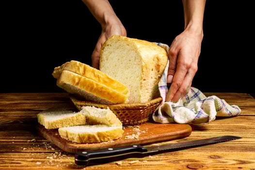 Female hands serving fresh white homemade bread in a basket on a wooden table. Homemade cakes, pastries. photo