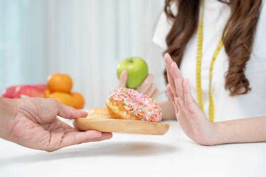 Diet and dieting. Beauty slim female body confuse donut. Woman in exercise clothes achieves weight loss goal for healthy life, crazy about thinness, thin waist, nutritionist. photo