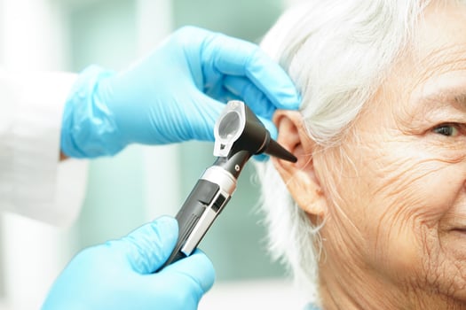 Otolaryngologist or ENT physician doctor examining senior patient ear with otoscope, hearing loss problem. photo