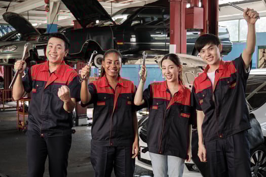 Multiracial professional mechanic workers team after work celebrating automotive repair jobs success, hand raises with fixing tools with cheerful smiles and look at camera at a service car garage. photo