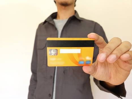 Man Holding and showing an orange credit card photo