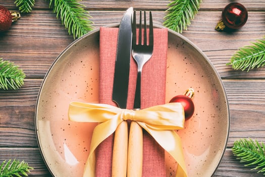 Top view of New Year dinner on festive wooden background. Composition of plate, fork, knife, fir tree and decorations. Merry Christmas concept photo