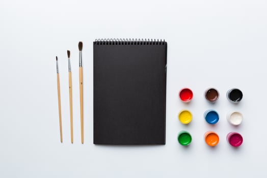 Album pages and paints, pencils, brush on a colored background. Top view with empty space. workplace for creativity. home teaching concept drawing photo