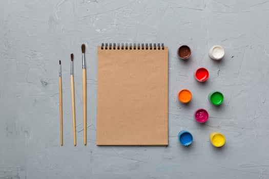 Album pages and paints, pencils, brush on a colored background. Top view with empty space. workplace for creativity. home teaching concept drawing photo
