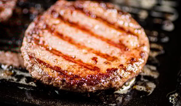 Cooking a delicious grilled burger on a pan with oil bubbles. photo