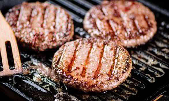 Cooking a delicious grilled burger on a pan with oil bubbles. photo