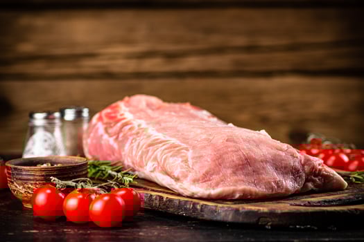 Raw pork on a cutting board with fresh tomatoes. photo