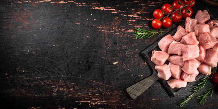 Pieces of raw pork on a cutting board with tomatoes. photo