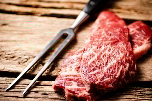 Fresh raw steak with fork. photo