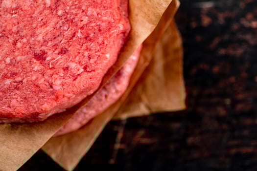 Raw burger on paper. On a rustic dark background. photo