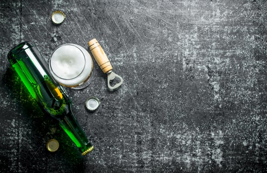 Beer in a glass and a glass bottle with opener. photo