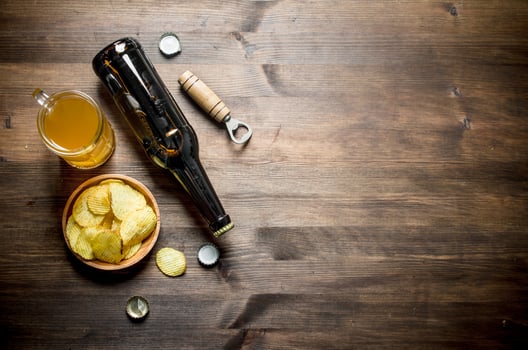 Beer in a bottle and a glass with chips and opener. photo