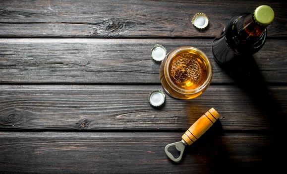 Beer in a glass and a bottle with opener and covers. photo