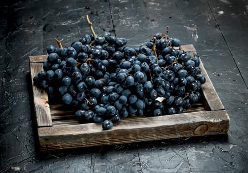 Black grapes on a wooden tray. photo