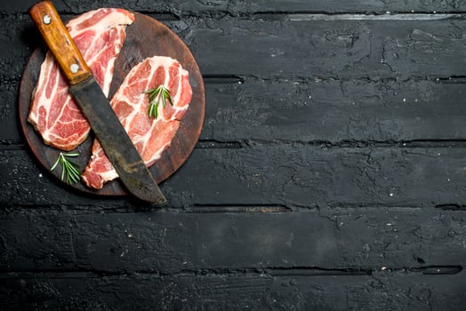 Raw pork steak with an old knife on a cutting Board. photo