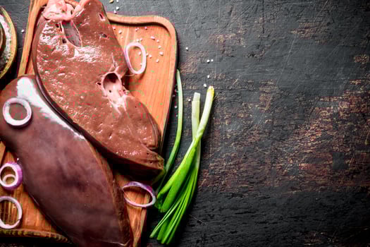 Fresh raw liver with onion rings and green onions. photo