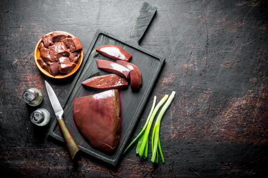 Pieces of raw liver in a plate and on a cutting Board. photo