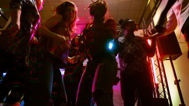 POV of friends dancing at disco party, enjoying social gathering with modern clubbing music on dance floor. Group of people having fun together at dance event in discotheque. Handheld shot. photo
