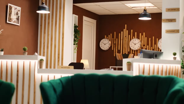 Empty stylish rustic travel vacation accommodation lounge interior with luxurious green furniture ready to welcome guests. Hotel lobby with check in counter desk, jib up shot photo