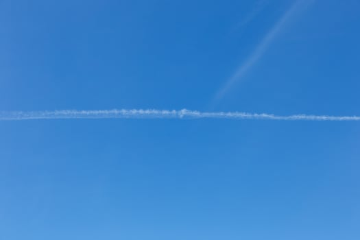 White trail from the plane against the blue sky. photo