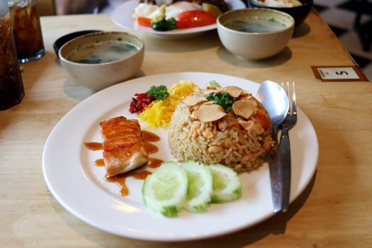 Salmon fried rice on white dish with salmon fillet grilled , cucumber slice, omelette, chilli and soup on wood table, Thailand. photo