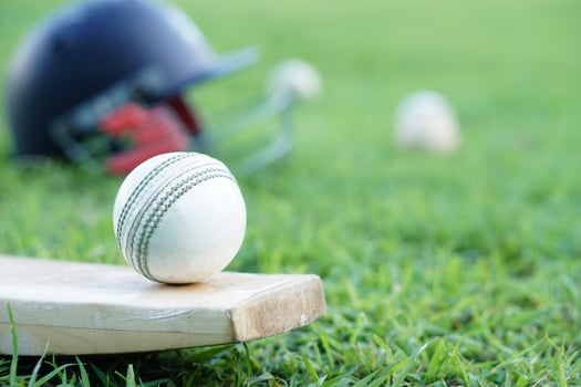 Cricket kits, helmet, cricket balls and bat on grass field. Concept, sport equipment. Well known competitive sport. Cricket is a bat-and-ball game played between two teams of eleven players on a field photo