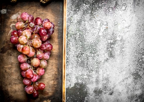 bunch of red grapes on a wooden tray. photo