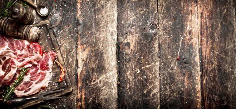 Raw meat background. Pieces of raw steak with spices and herbs. On wooden background. photo