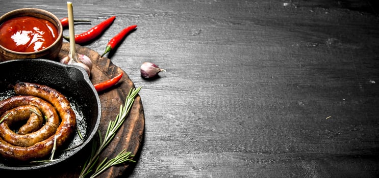 Sausage in a frying pan with hot tomato sauce. photo
