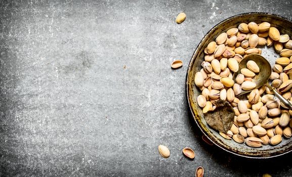 Pistachios in an old pan with a ladle. photo